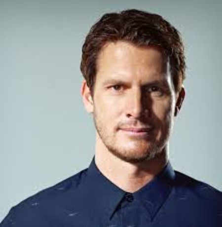 Daniel Tosh in a dark blue shirt poses for a picture.